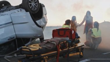 Crash trafik kazasında araba Burning: sağlık görevlisi ekibi yaralı anne ve genç kızı acil Ilk yardım gerçekleştirin. Oksijen maskesi vererek ve travma kontrol