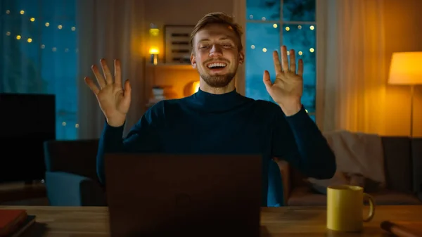 Το βράδυ: ευτυχισμένο νεαρό άντρα χορεύει ενώ κάθεται στο γραφείο του, χρησιμοποιεί φορητό υπολογιστή και ακούει μια μουσική. — Φωτογραφία Αρχείου