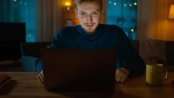 À Noite: Jovem Estudante Inteligente Estudos em Casa, Usa Laptop Enquanto Sentado em Sua Mesa e Cuidadosamente Reading . — Fotografia de Stock