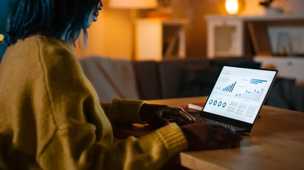 통계 인포그래픽을 보여주는 노트북 컴퓨터는 거실의 책상에 서 있습니다. 배경에 따뜻한 조명과 아늑한 거실. — 스톡 사진