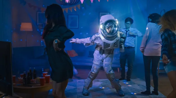 På college House kostym Party: kul kille klädd i rymden kostym danser av, gör robot Dance modern flyttar. Med honom vackra flickor och pojkar dansar i neonljus. — Stockfoto