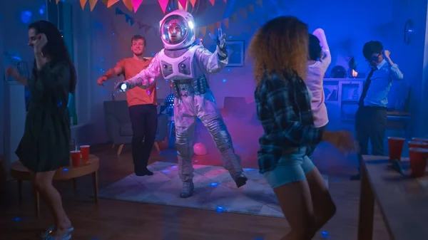 Kolej Evi kostüm partisi: eğlenceli adam giyim uzay Suit dans, robot dansı modern Moves Doing. Onu güzel kızlar ve çocuklar Neon ışıklar dans ile. — Stok fotoğraf