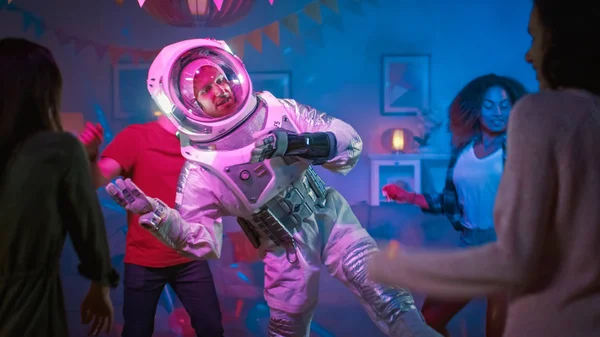 På college House kostym Party: kul kille klädd i rymden kostym danser av, gör robot Dance modern flyttar. Med honom vackra flickor och pojkar dansar i neonljus. — Stockfoto