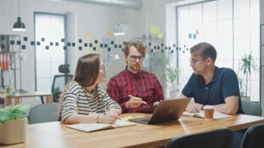 Genç Kadın ve İki Erkek İş Arkadaşı Arkadaşça Buluşup Yeni İş Fikirlerini Tartışıyor. Daire Ofisi Yaratıcı Ajansı 'nda Birlikte Çalışmanın Kolay Atmosferi. Laptop ve Tablet 'te Not Alırlar.