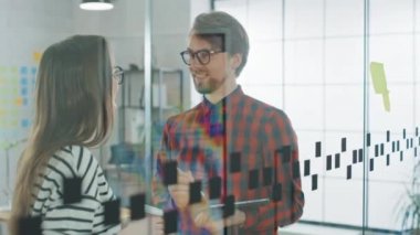 Genç adam ile tablet ve kadın Takeaway kahve stand ile cam duvar önce notlar ve tartışmak Iş fırsatları. Creative Agency 'de çalışıyorlar. Meslektaşları arasında dost Ilişki.