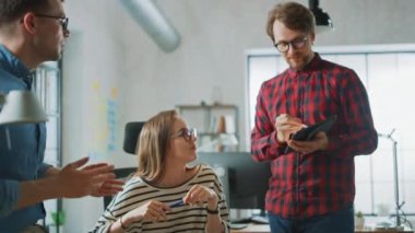 Genç kadın ve Iki erkek meslektaşları dostu bir toplantı ve yeni Iş fikirleri tartışarak yavaş Motion Shot. Loft ofis Creative Agency easygidiş coworking atmosfer. Onlar dizüstü ve tablet notlar olun.