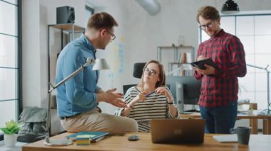 Genç kadın ve Iki erkek meslektaşları dostu bir toplantı ve yeni Iş fikirleri tartışarak yavaş Motion Shot. Loft ofis Creative Agency easygidiş coworking atmosfer.
