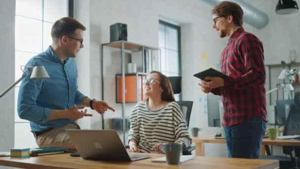 Genç kadın ve Iki erkek meslektaşları dostça bir toplantıya sahip ve yeni Iş fikirleri tartışıyor. Loft ofis Creative Agency easygidiş coworking atmosfer. Onlar başarılı bir çözüm kutlamak. — Stok video