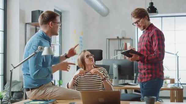 Mujer joven y dos colegas varones teniendo una reunión amistosa y discutiendo nuevas ideas de negocios. Ambiente de Coworking Easygoing en Loft Office Creative Agency. Celebran una solución exitosa . — Vídeo de stock