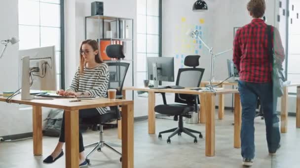 Jonge knappe creatieve collega komt 's ochtends naar zijn kantoor bureau. Hij draagt een schoudertas en werkt in een creatief bureau. Easygoing sfeer en diverse collega's in het Loft kantoor. — Stockvideo