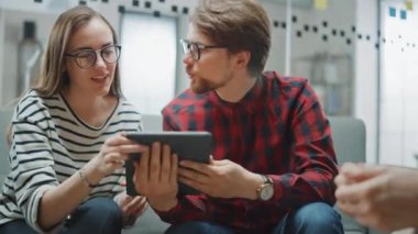 Genç Kadın ve İki Erkek İş Arkadaşı Arkadaşça Buluşup Yeni İş Fikirlerini Tartışıyor. Daire Ofisi Yaratıcı Ajansı 'nda Birlikte Çalışmanın Kolay Atmosferi. Evraklara ve tabletlere bakarlar..