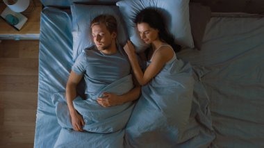 Gece üst görünüm yatak: çekici genç çift birlikte uyuyan, kollarda birbirlerini tutarak, kucaklayan. Sabah güneş aydınlatmak Oda ilk Rays pencere Trough