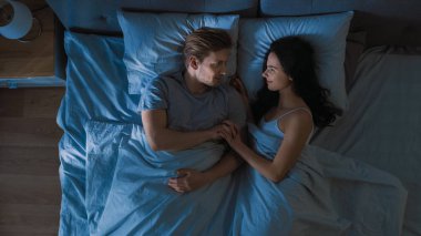 Yatakta gece sevimli genç çift yatakta uykuya düşmek önce, onlar birbirlerine şefkat bakmak, Içtenlikle ve Smile konuşun. Aşk genç Insanlar.