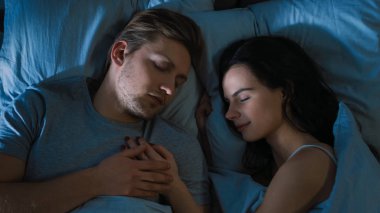 Gece üst görünüm yatak: çekici genç çift birlikte uyuyan, kollarda birbirlerini tutarak, kucaklayan. Sabah güneş aydınlatmak Oda ilk Rays pencere Trough