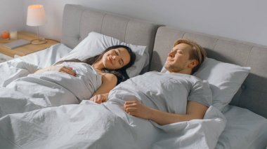 Sabah sevimli genç çift yatakta Cozily Sleeping içinde. Aşık genç Insanlar. Sabah erken gün güneşi pencereden parlar.