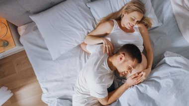 Mutlu genç çift yatakta birlikte cuddling, Genç kadın hamile, sevgi dolu partner eğilir ve bir bebek hareket dinler ve Belly kalp atışı 's. Aile yaşamının ihale ve sevgi dolu anları.