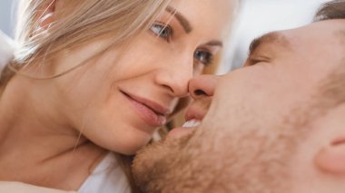 Mutlu Genç Couple cuddling birlikte içinde bu yatak, gülümseyen ve bakarak birbirlerine. Sarışın kadın ve onu uygun sevgi dolu ortak yaşayan Ihale ve sevgi dolu Moments birlikte yaşam. Yüz yakın çekim.