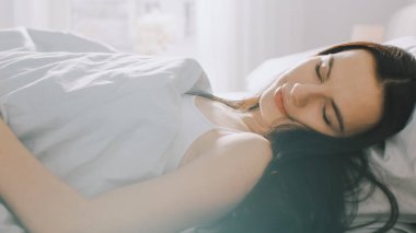 Erken sabah güneş ışınları onu aydınlatırken çekici esmer Cozily yatağında uyuyor. Güzellik Sleeping sıcak, rahat ve tatlı resim