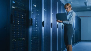 Veri merkezi 'nde: bir laptop üzerinde bakım programı çalışan kadın BT teknisyeni, operasyonel sunucu raf optimum Işleyişini kontrol eder. Modern High-Tech telekomünikasyon operasyonel süper bilgisayar.