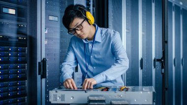 Modern veri merkezi: It mühendisi koruyucu Muffs giyen sunucu raf için yeni donanım yükler. Bu bakım yapıyor uzman, veritabanı sisteminin Istikrarlı Işleyişi için tanılama çalışan.