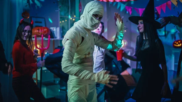 Хеллоуїн костюм учасника: старий худий і перев'язана танцями мумія. У фоновому режимі зомбі, смерть, відьма і вона диявол весело провести час в Monster Party прикрашену кімнату — стокове фото