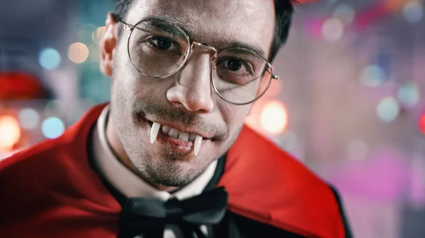 Festa in costume di Halloween: ritratto ravvicinato del conte Dracula sorridente raccapricciante, mostra le sue sanguinose zanne mortali. Sullo sfondo Stanza decorata tematicamente con roba spaventosa. Colori blu mortali — Foto Stock