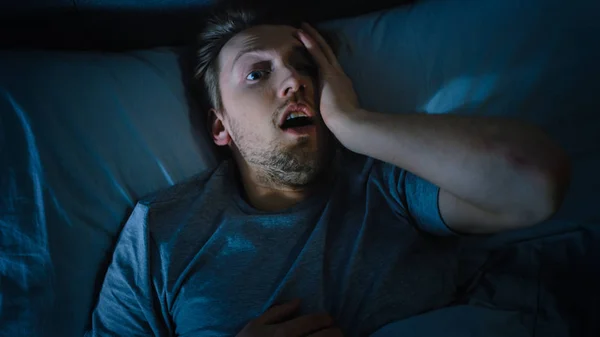 Top View of a Young Man in Bed at Night Having Terrible Nightmare, He Wakes Up Scared and Covered in Sweat. — Stock Photo, Image