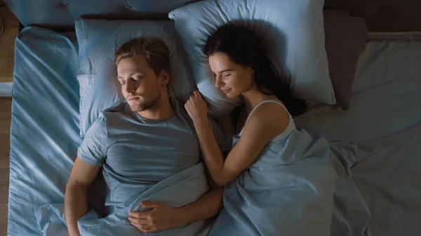 Top View Bed w nocy: atrakcyjna Młoda para Spanie razem, trzymając się nawzajem w ramionach, obejmując. Pierwsze promienie porannego słońca oświetlić Pokój koryto okna — Zdjęcie stockowe