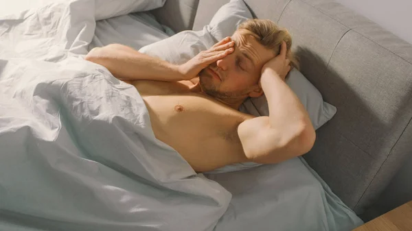 Handsome Fair Boy Sleeping Cozily in Bed, Slowly Wakes up and Stretches Lazily in a Bed. Young and Fit Caucasian Man Greeting New Day. Early Morning Sun Shines Through the Window — Stock Photo, Image