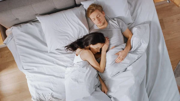 Aranyos fiatal pár édesen alszik az ágyban, lány tenderly cuddling és Emracing barátjával, míg Dreaming. Kora reggeli nap süt az ablakon. — Stock Fotó