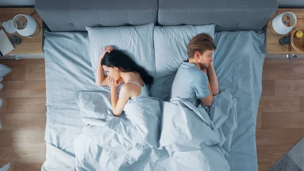 Rozhádaný mladý pár v posteli, mladí lidé leželi stranou a leželi na svých bocích a drželi se za zášť a urážet — Stock fotografie