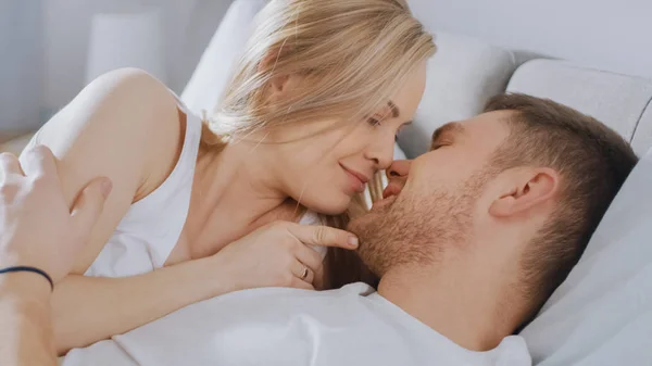 Happy Young Couple Cuddling Together in the Bed, Kissing and Smiling. Beautiful Blonde Female and Her Fit Loving Partner Experiencing Tender and Loving Moments of Living Together. — Stock Photo, Image