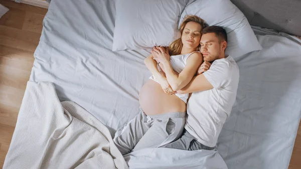 Boldog ifjú pár alszik együtt a Bed, Sweet Loving fiatalok Holding egymást, míg alszik. Gyönyörű nő terhes, szerető partner támogatja őt azáltal, hogy ott érte. — Stock Fotó