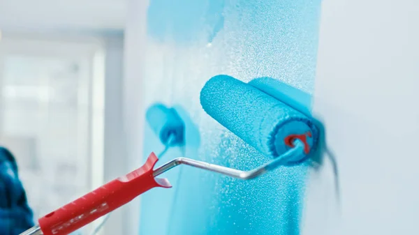 Close-up shot van een muur die wordt beschilderd met een roller. Kleur van de verf is licht blauw. Vlakke renovaties thuis. — Stockfoto