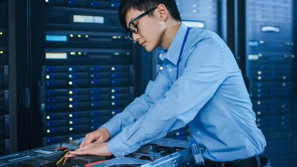 In the Modern Data Center: IT Technician Working with Server Racks, on a Pushcart Installing New Hardware (en inglés). Ingeniero haciendo mantenimiento y diagnóstico de la base de datos . — Foto de Stock