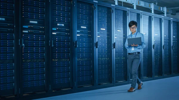 Nel moderno Data Center: IT Engineer che lavora con rack server, utilizza laptop per la manutenzione e la diagnostica. Verifica della stabilità del sistema — Foto Stock