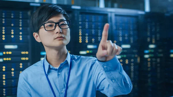 In the Modern Data Center: Portrait of IT Engineer Working With Touch Screen Device, Doing Touching Gesture (en inglés). En los bastidores del servidor de trabajo de fondo con luces led parpadeantes . —  Fotos de Stock