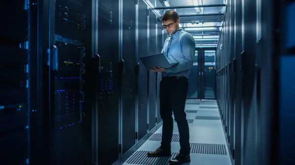 W Data Center IT Engineer stoi przed pracy rack Server doing rutynowej konserwacji sprawdzić i Diagnostyka za pomocą laptopa. Koncepcja przetwarzania w chmurze, sztuczna inteligencja, superkomputer — Zdjęcie stockowe