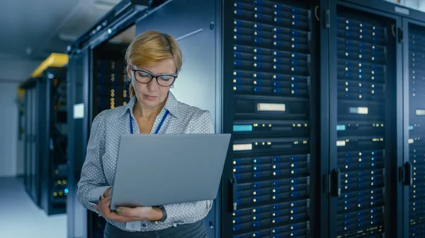 Portret strzał w centrum danych: Kobieta IT technik uruchomiony program konserwacji na laptopie, kontroluje operacyjną rack Server optymalne funkcjonowanie. Nowoczesne High-Tech telekomunikacyjnych centrum danych. — Zdjęcie stockowe