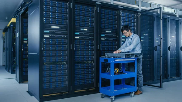 No Data Center Moderno: Técnico de TI Trabalhando com Racks de Servidor, em um Pushcart Vários Equipamentos Necessários para Instalação de Novos Discos Rígidos, Fazendo Manutenção e Diagnóstico de Hardware . — Fotografia de Stock