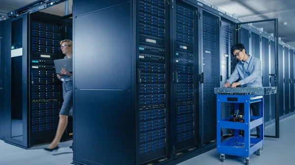 In het moderne Data Center: team van IT-technici die werken met server racks, man met pushcart verandert defecte harde schijven, hardware-onderhoud en diagnostiek. — Stockfoto