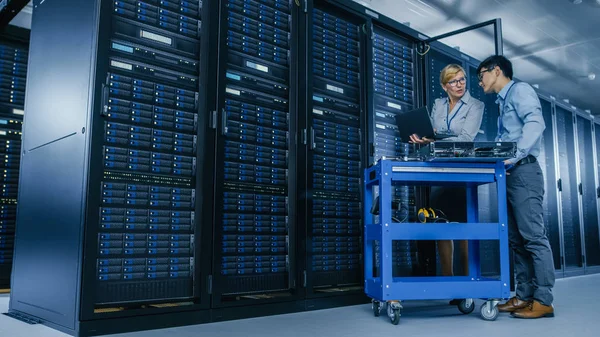 A modern Data Center: mérnök és szakember munka Server racks, egy Pushcart berendezések új hardver telepítése. Az adatbázis karbantartása és diagnosztikája során specialisták. — Stock Fotó