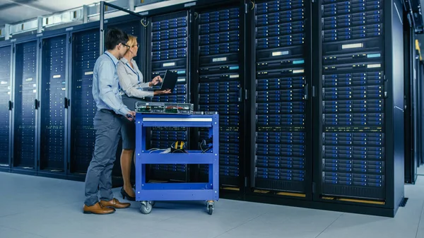 No Data Center Moderno: Engenheiro e Especialista em TI Trabalhe com Racks de Servidor, em um Equipamento Pushcart para Instalação de Novos Hardware. Especialistas em Manutenção e Diagnóstico do Banco de Dados . — Fotografia de Stock