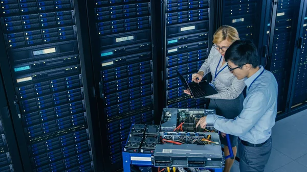 A modern Data Center: mérnök és szakember munka Server racks, egy Pushcart berendezések új hardver telepítése. Az adatbázis karbantartása és diagnosztikája során specialisták. — Stock Fotó