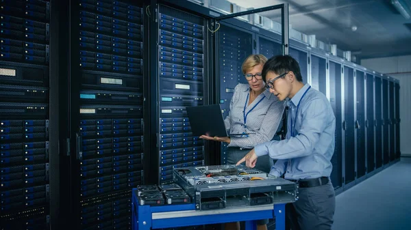 Dans le centre de données moderne : Ingénieur et spécialiste de l'informatique travaillent avec des racks de serveur, sur un équipement Pushcart pour installer du nouveau matériel. Spécialistes Entretien et diagnostic de la base de données . — Photo