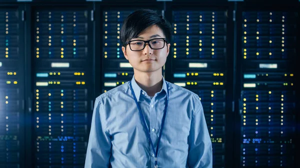 In the Modern Data Center: Portrait of IT Engineer Standing with Server Racks Behind Him (en inglés). Especialista en TI profesional que trabaja en un centro de datos moderno con tecnologías innovadoras . —  Fotos de Stock