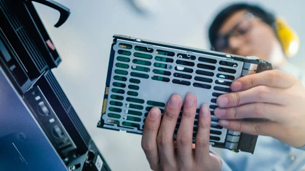 In het Data Center: IT Engineer installeert nieuwe HDD harde schijf en andere hardware in server rack apparatuur. IT specialist doet onderhoud, voert diagnostiek uit en werkt hardware bij. Lage hoek. — Stockfoto