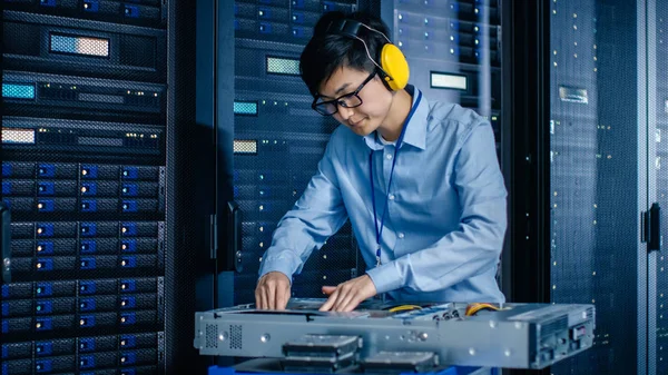 Dans le centre de données moderne : l'ingénieur informatique portant des manchons de protection installe un nouveau matériel pour le rack serveur. Spécialiste de l'informatique Entretien, mise à jour du matériel pour un fonctionnement stable du système de base de données . — Photo