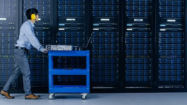 I Modern Data Center: IT Engineer Doing Vedligeholdelse og Diagnostik. Skubber indkøbskurv sammen Server Racks, åbner kabinet til at installere nyt hardware til planlagt systemopdatering, udskiftning af udstyr . - Stock-foto