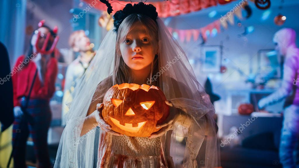 Festa in costume di Halloween: bambina sorridente con un vestito da sposa  bianco insanguinato con testa